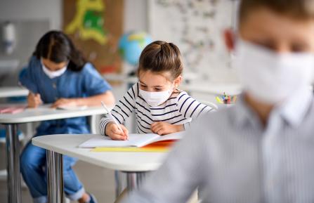 young girl in classroom wearing a mask