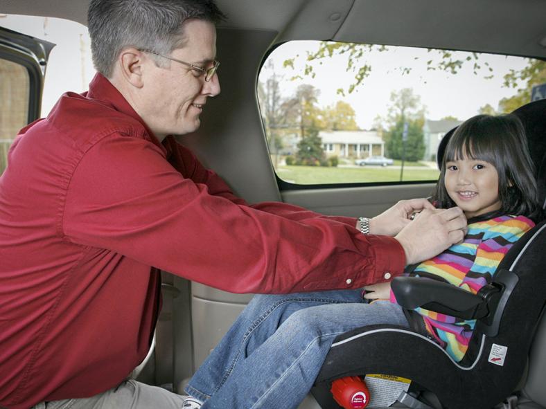 Father adjusting seat belt for child